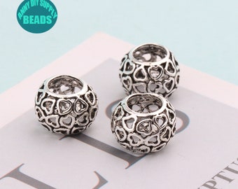 May include: Three silver-toned metal beads with a heart-shaped design. The beads are hollow and have a round shape.