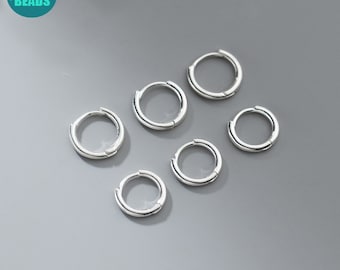 May include: Six silver hoop earrings, each with a smooth, circular design. The earrings are arranged in a semi-circle pattern on a gray background.