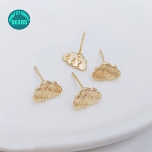 Puede incluir: Cuatro pendientes de botón dorados en forma de nube. Los pendientes tienen una superficie texturizada y un poste para la inserción. La imagen también incluye un logotipo turquesa y blanco que dice "ANNY DIY SUPPLY BEADS".