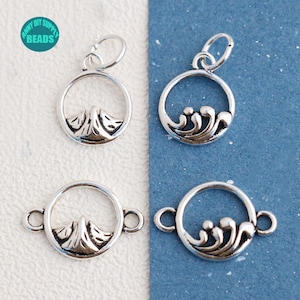 May include: Four silver charm pendants, two with a mountain design and two with a wave design. The charms are round and have a loop at the top for attaching to a chain or bracelet.