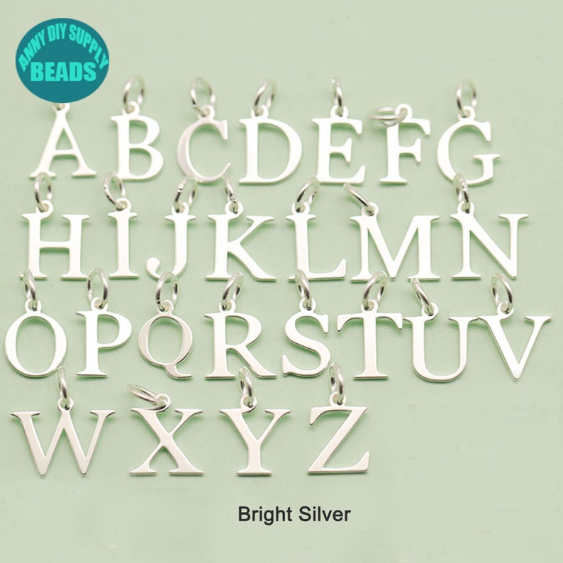 May include: A set of 26 silver letter charms, each letter of the alphabet from A to Z. The charms are on a light green background. The text "Bright Silver" is below the charms.