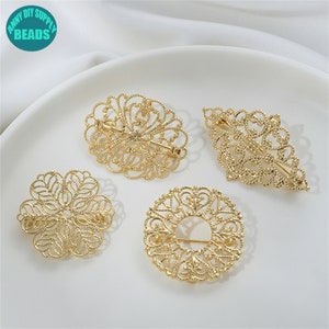May include: Four gold-toned metal filigree brooches in different shapes: oval, round, diamond, and flower. The brooches are delicate and intricate, with a detailed design.