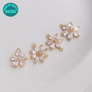 May include: Four gold-tone flower charms with clear crystal accents. The charms have two jump rings for attaching to jewellery.
