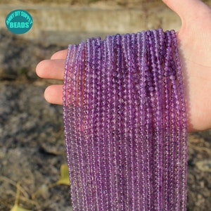 K&ouml;nnte beinhalten: Eine Str&auml;hne aus violetten Amethystperlen, etwa 4 mm im Durchmesser, auf einem durchsichtigen Faden aufgereiht. Die Perlen sind glatt und durchscheinend, mit einem leichten Schimmer.