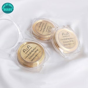 Könnte beinhalten: Drei transparente Plastikbehälter mit goldenen Drahtspulen. Jeder Behälter trägt ein Etikett mit der Aufschrift "A.LA accessories Copper Wire" und gibt die Drahtstärke in Millimetern an.