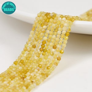 Pode incluir: Um fio de contas de pedras preciosas amarelas. As contas são facetadas e têm uma forma ligeiramente irregular. As contas são enfiadas em um fio transparente e estão prontas para serem usadas para fazer joias.