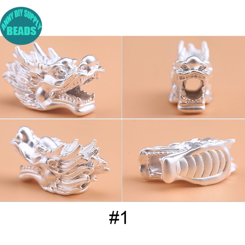 May include: Silver dragon head charm with intricate details. The charm is shown from four different angles, showcasing its design.