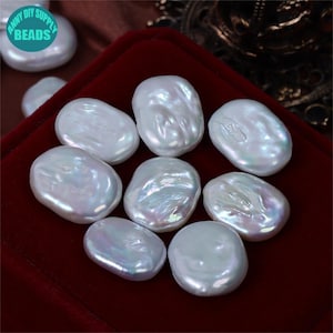 May include: Eight white oval-shaped baroque pearls with iridescent sheen. The pearls are arranged on a red velvet surface.