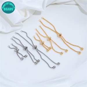 Könnte beinhalten: Mehrere gold- und silberfarbene verstellbare Armbandketten mit kleinen Kugelakzenten. Die Ketten werden auf einer weißen Oberfläche präsentiert. Das Bild enthält ein rundes Logo mit dem Text "ANNY DIY SUPPLY BEADS".