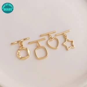 May include: Four gold-toned metal toggle clasps with different pendant shapes: a square, a heart, a star, and a geometric square.