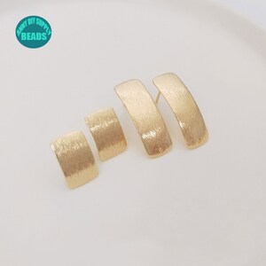 Könnte beinhalten: Drei Paar goldfarbene Ohrringe mit gebürsteter Oberfläche. Die Ohrringe sind rechteckig und haben ein leicht gebogenes Design.