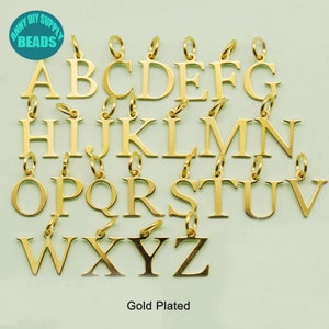 May include: Gold-plated alphabet letter charms, A through Z, with jump rings. Each charm is about 1 inch tall.