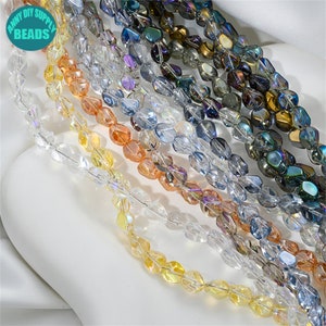 Puede incluir: Surtido de cuentas de vidrio iridiscente en varios colores, incluyendo transparente, azul claro, amarillo claro y naranja claro. Las cuentas son facetadas y tienen forma de lágrima.