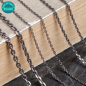 Può includere: Primo piano di diverse collane a catena argentate con vari design di maglie. Le catene sono esposte su uno sfondo neutro, mostrando la loro consistenza e i dettagli. L'immagine include un logo che dice "ANNY DIY SUPPLY BEADS".