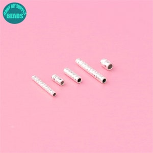 May include: Five silver metal tube beads with a textured surface. The beads are arranged in a row from largest to smallest.