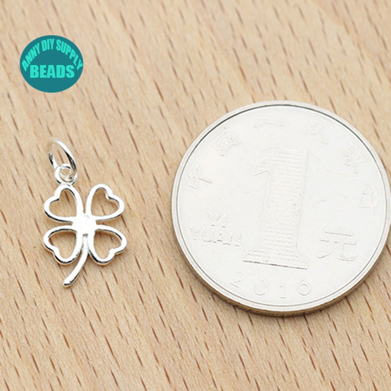May include: Silver four-leaf clover charm pendant, shown next to a Chinese yuan coin for size comparison.