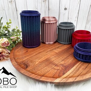 May include: Five different colored cylindrical containers with a ribbed design. The containers are arranged on a wooden tray. The containers are made of plastic or metal and have a variety of colors, including blue, pink, gray, red, and purple.