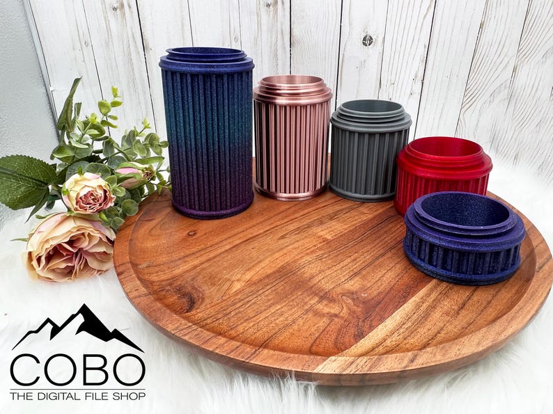 May include: Five different colored cylindrical containers with a ribbed design. The containers are arranged on a wooden tray. The containers are made of plastic or metal and have a variety of colors, including blue, pink, gray, red, and purple.