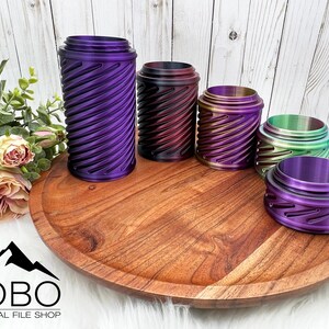 May include: Five iridescent metal containers with a swirling pattern on a wooden tray. The containers are in shades of purple, red, gold, green, and blue.