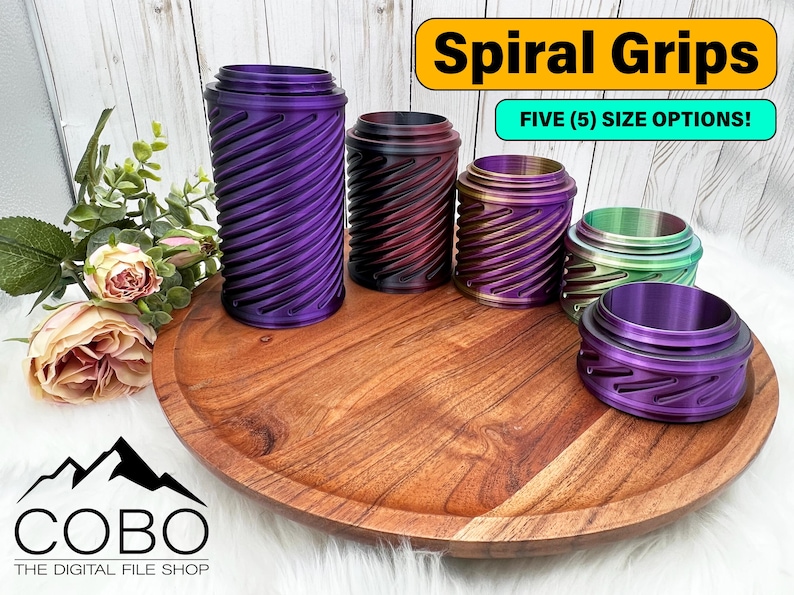 Op de afbeelding: Een verzameling van vijf spiraalvormige handgrepen in verschillende kleuren, waaronder paars, zwart en groen, gepresenteerd op een houten dienblad. De tekst "Spiral Grips" en "FIVE (5) SIZE OPTIONS!" zijn zichtbaar.