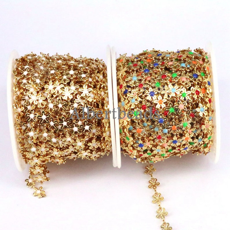 May include: Two spools of gold-colored metal chain with flower-shaped links. One spool has plain gold flowers, the other has flowers with colorful enamel centers.