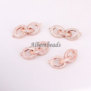 May include: Four rose gold infinity charm connectors with clear cubic zirconia stones. The connectors are designed to be used in jewelry making.
