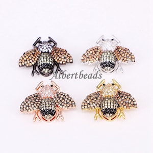 May include: Four bee-shaped charms with crystal accents. The charms are in black, silver, rose gold, and gold finishes.