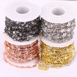 May include: Four spools of chain with square-shaped crystals. The chains are silver, black, rose gold, and gold.