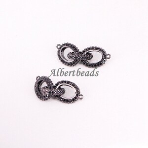 May include: Two black metal chain connectors with small black stones. The connectors are oval shaped and have a loop on each end.