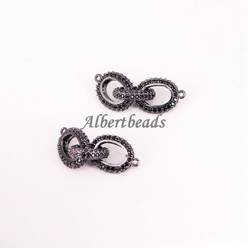 May include: Two black metal chain connectors with small black stones. The connectors are oval shaped and have a loop on each end.