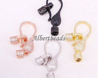 May include: Four different colored metal clasps with clear crystal accents. The clasps are in black, rose gold, silver, and gold.