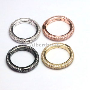 May include: Four silver, rose gold, black, and gold round clasps with clear crystal accents. Each clasp is a circle with a hinged opening.