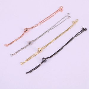 Peut inclure: Quatre cordons de bracelet réglables avec différentes finitions métalliques : or rose, argent, or et noir. Chaque cordon a deux petites perles aux extrémités et une perle plus grosse au milieu.