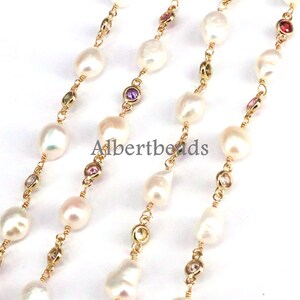 May include: A gold chain necklace with white pearls and colorful gemstones. The chain is made of small, linked gold beads. The pearls are round and smooth, and the gemstones are faceted and sparkly.