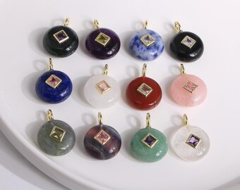 Puede incluir: Una colección de doce colgantes de piedras preciosas con aros dorados. Cada colgante redondo presenta una piedra de diferente color, incluyendo verde, morado, azul y rosa, con una gema de corte cuadrado en el centro.