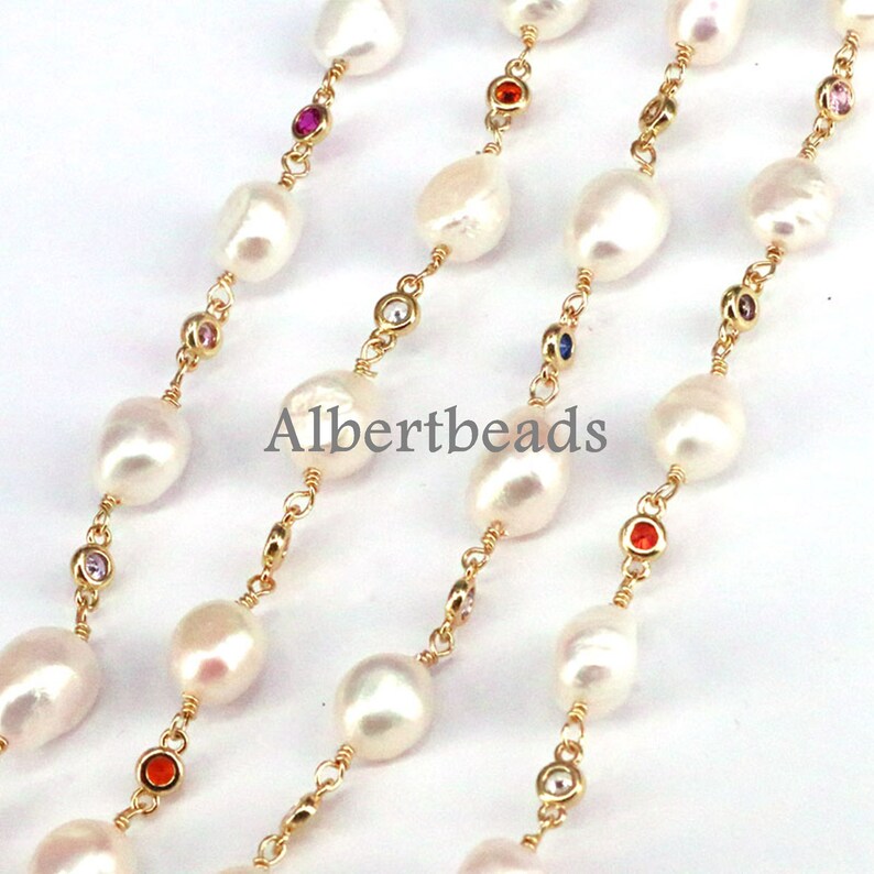May include: A gold chain necklace with white pearls and colorful gemstones. The necklace is layered and features a repeating pattern of pearls and gemstones.