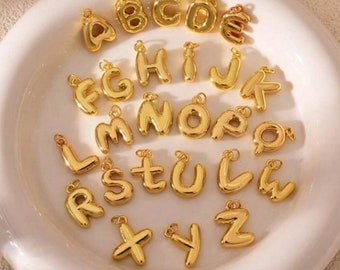 May include: A set of 26 gold-colored alphabet letter charms. Each letter is in a balloon-like shape and has a loop for attaching to a necklace or bracelet.