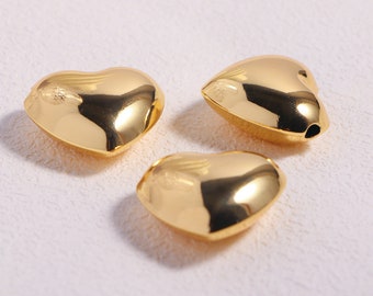 May include: Three gold heart-shaped beads with a shiny finish. The beads have a hole in the top for stringing.
