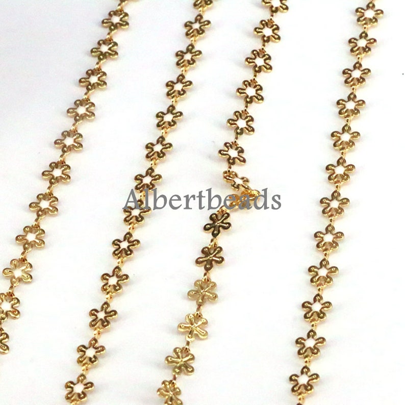 May include: Gold chain with small flower-shaped links. The chain is made of metal and has a shiny finish.