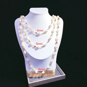 May include: Three pearl necklaces with different sized pearls, 4mm, 5mm, and 6mm, on a white mannequin. Each necklace has small colorful gemstones interspersed throughout.