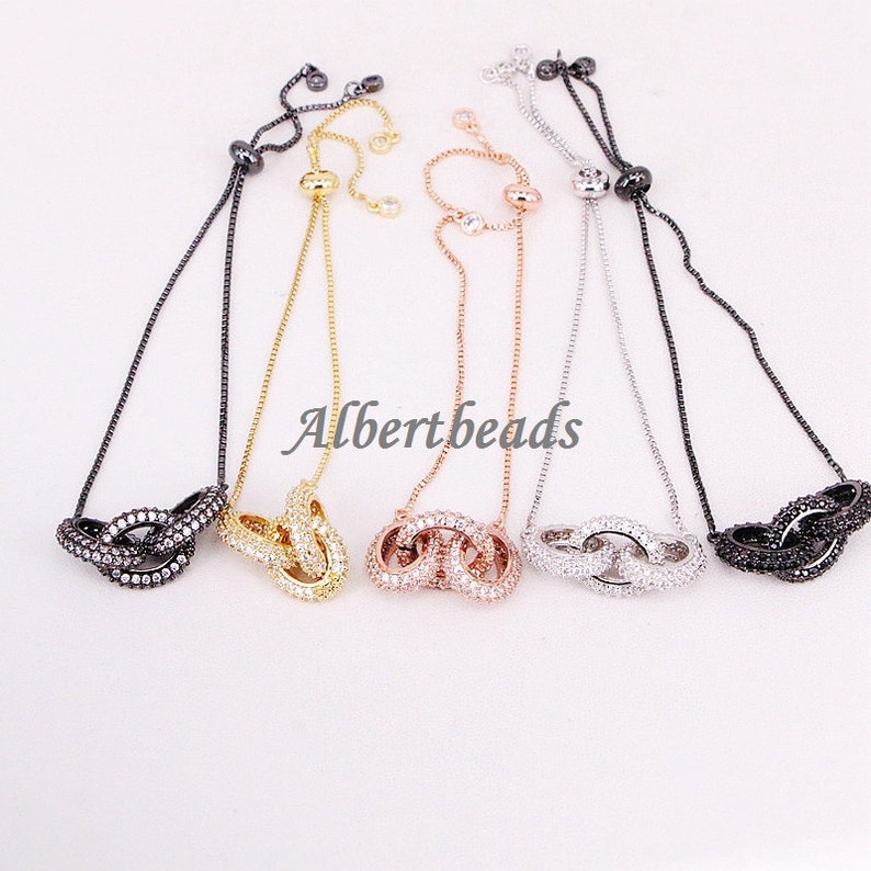 May include: Five adjustable bracelets with a double circle design, each circle is encrusted with clear rhinestones. The bracelets are available in black, gold, rose gold, silver, and gunmetal.
