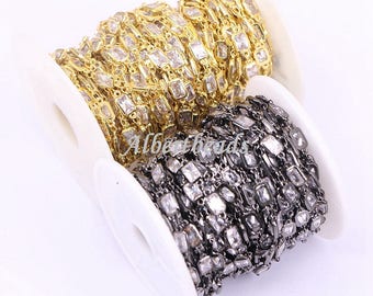 May include: Two spools of chain with square-shaped clear crystals. One spool has a gold chain and the other has a black chain.