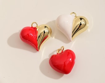 Könnte beinhalten: Drei herzförmige Anhänger in Rot, Weiß und Gold. Zwei Anhänger sind geteilt, eine Hälfte goldfarben und die andere rot oder weiß. Der dritte Anhänger ist einfarbig rot. Jeder Anhänger hat eine goldene Schlaufe zum Aufhängen.
