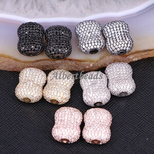 Pode incluir: Conjunto de seis contas de barril de dupla face com engaste pavé de zircónias cúbicas transparentes. As contas estão disponíveis em preto, prata e ouro rosa.