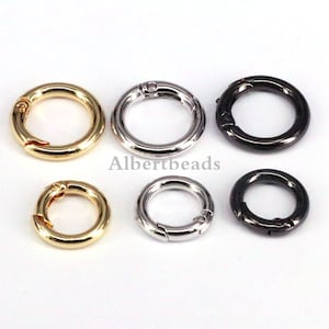 Op de afbeelding: Zes metalen sleutelringen in goud, zilver en zwart. De ringen zijn open en hebben een veerbelaste sluiting.