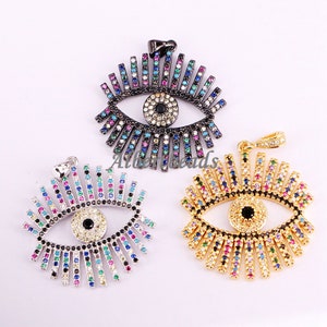 May include: Three evil eye pendants with colorful crystal accents. The pendants are in gold, silver, and black finishes.