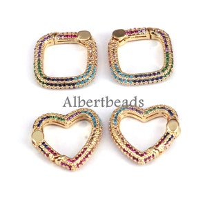 May include: Four gold-toned metal clasps with colorful crystal accents. Two clasps are square shaped and two are heart shaped.