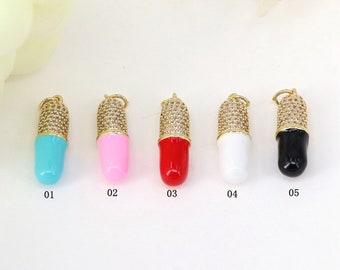 May include: Five gold pill charms with different colored enamel. The charms are numbered 01 through 05. The charms are turquoise, pink, red, white, and black.