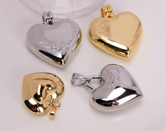 May include: Four heart-shaped pendants in gold and silver tones. Two pendants are silver, and two are gold. The pendants have a shiny, reflective surface. The pendants are likely for jewelry making or crafting.