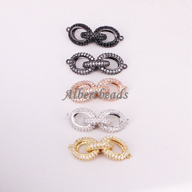 May include: Four different colored metal connector clasps with clear crystal embellishments. The clasps are in black, silver, rose gold, and gold.